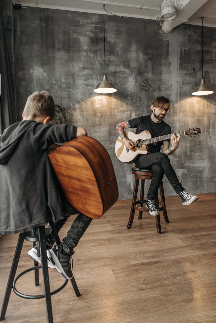 Man teaching a boy to play guitar in a contemporary music studio.